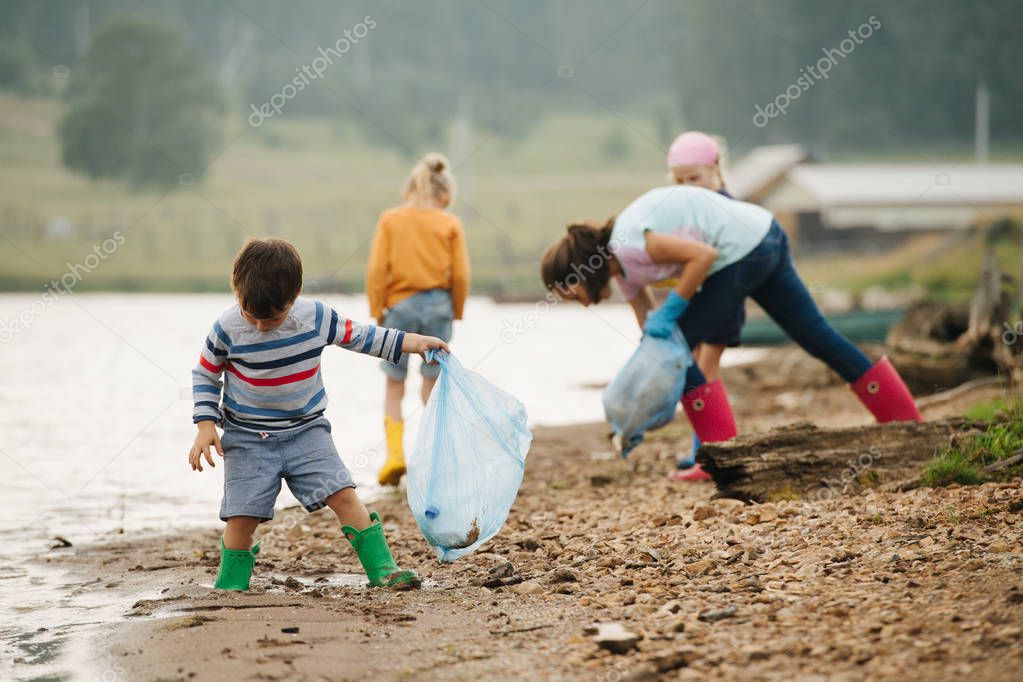 little boy collecting garbage with group of kids