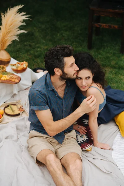 Pareja enamorada, haciendo picnic en el césped en su patio, mirándose el uno al otro —  Fotos de Stock