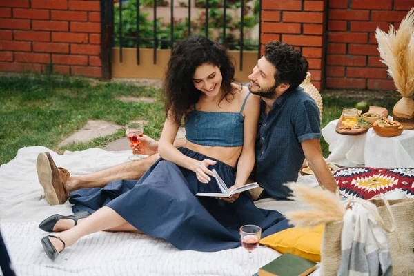 Pareja enamorada, bebiendo vino rosa, haciendo picnic en el césped en su patio —  Fotos de Stock