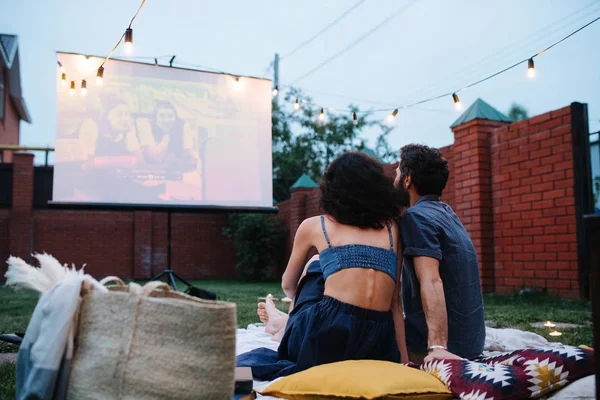 Couple in love watching a movie, in twilight, outside on the lawn in a courtyard — Stock Photo, Image