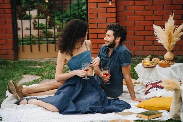 Pareja enamorada, bebiendo vino rosa, haciendo picnic en el césped en su patio —  Fotos de Stock