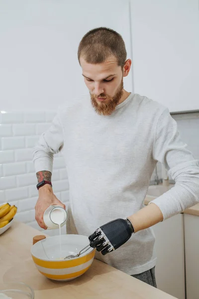 Молодий бородатий привабливий хлопець зі штучними кухарями кінцівок на кухні — стокове фото