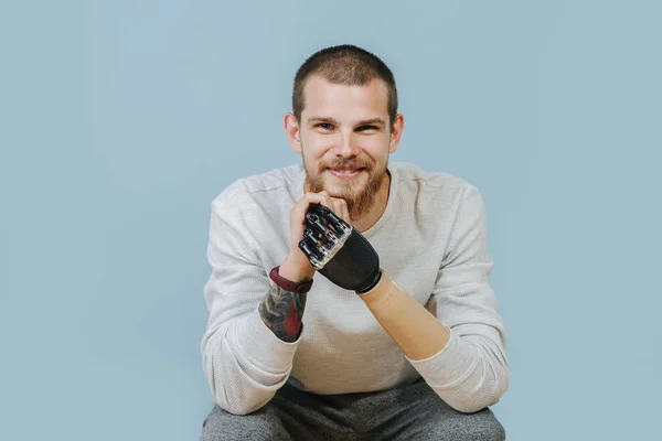 Jonge man met kunstmatige hand kijkt uit en glimlacht naar de camera — Stockfoto