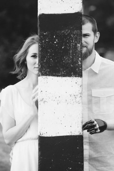 Молодой человек с протезной рукой и с женой смотрит из колонны — стоковое фото