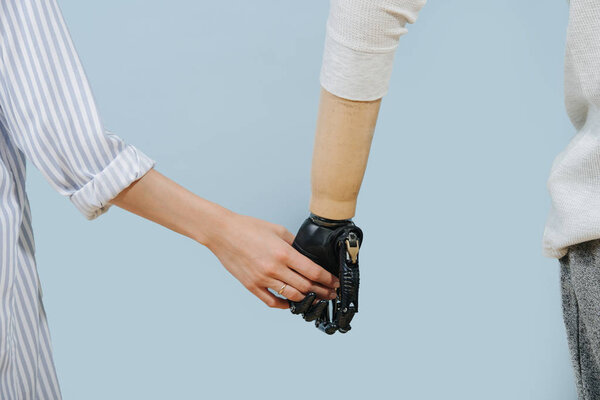 Съемка крупным планом человека с искусственной конечностью, держащего руки с женщиной-партнером
 