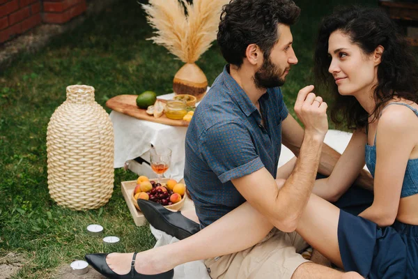 Pareja enamorada, haciendo picnic en el césped en su patio, mirándose el uno al otro —  Fotos de Stock