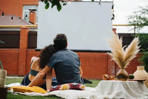 Para zakochany oglądając film, podczas pikniku na trawniku na dziedzińcu. — Zdjęcie stockowe