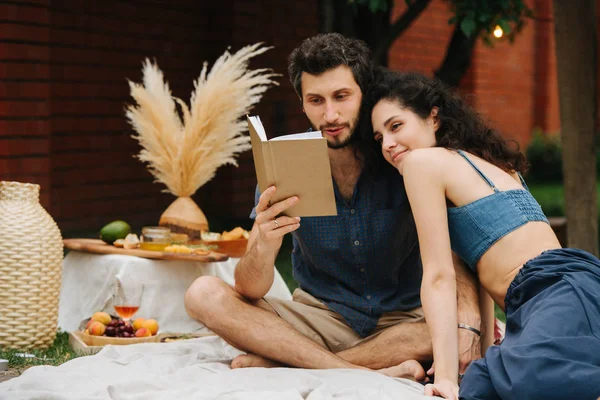 Aşık çift avlusunda çim piknik sırasında birlikte kitap okuyor — Stok fotoğraf