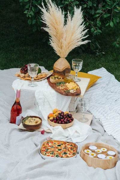 Mesa de aperitivos para picnic, llena de aperitivos. Paño blanco extendido sobre césped —  Fotos de Stock