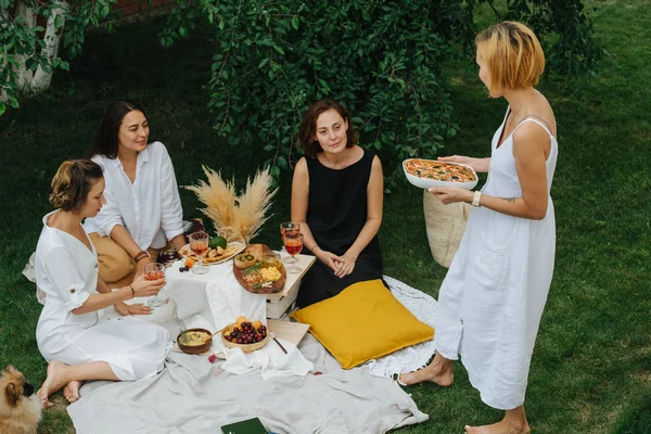 Young woman is bringing pizza for her three girlfriends. — Stock Photo, Image