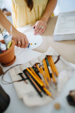 Genç kadın sanatçı, evde masanın arkasında palet yapma.