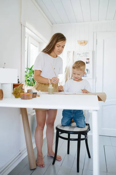 Young mother and first grade son are painting together at home — Stock Photo, Image