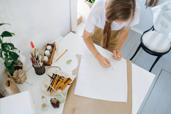 Jovem garota desenha de pé em uma mesa em uma oficina criativa — Fotografia de Stock