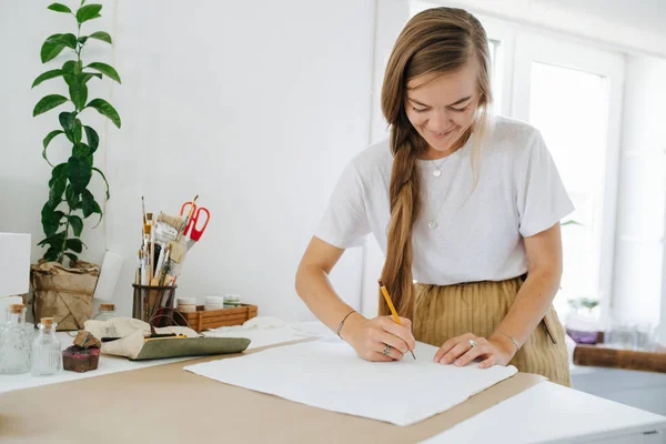 Joven artista dibujo en hoja, detrás de la mesa en casa . —  Fotos de Stock