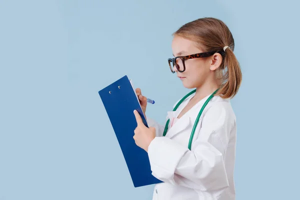 Χαμογελαστός κοριτσάκι που παίζει γιατρό, φορώντας μεγάλες λευκές ρόμπες με στηθοσκόπιο — Φωτογραφία Αρχείου