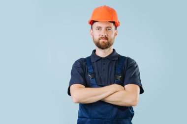 Turuncu kask ve mavi üniformalı kendine güvenen inşaat işçisi, elleri geçti