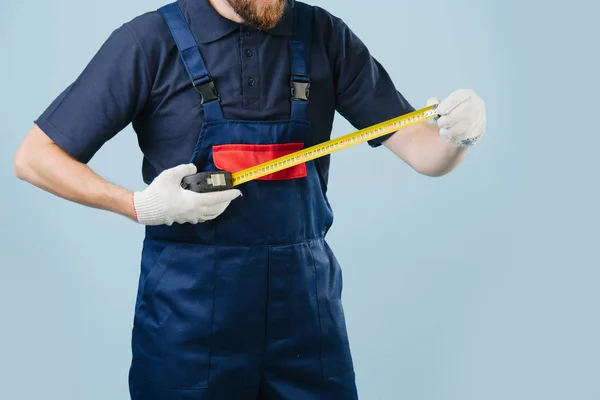 Trabalhador de serviço com medidor de fita nas mãos, vestido de uniforme — Fotografia de Stock