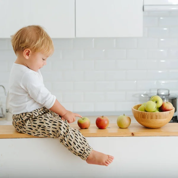 Jolly sarışın yürümeye başlayan çocuk araştırıyor, backet gelen elma ile oynar.