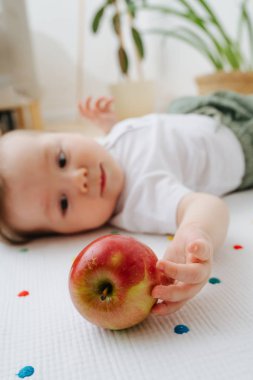 Bebek yerde yatan ve bir elma ile oynarken