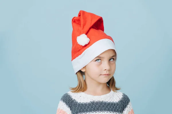 Porträt eines süßen kleinen Erstklässlers mit Weihnachtsmütze und Strickpullover. — Stockfoto