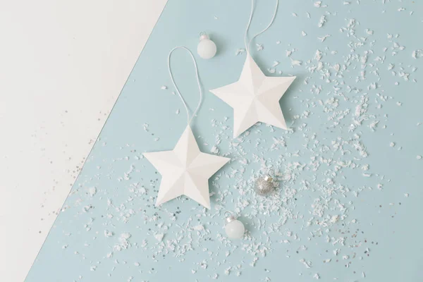 Bílé vánoční hvězdy a koule posypané sněhem napodobeninou přes modrou — Stock fotografie