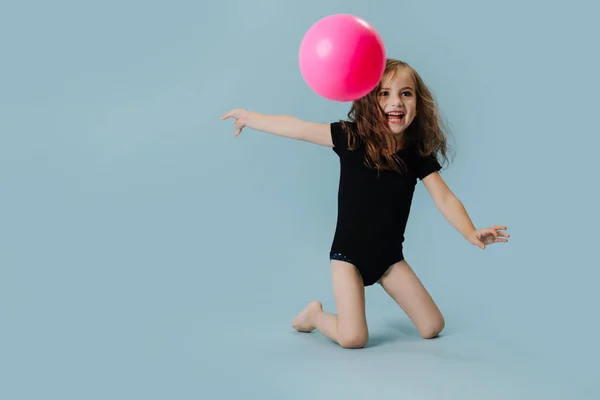 小女孩在黑色的利奥塔与粉红色的体操球在蓝色背景 — 图库照片