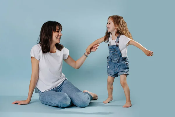 Mãe e filha passar o tempo, rindo juntos sobre fundo azul — Fotografia de Stock