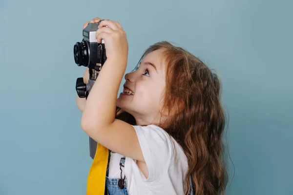 Ragazzina sta prendendo un'immagine con una macchina fotografica specchiata vintage su blu . — Foto Stock