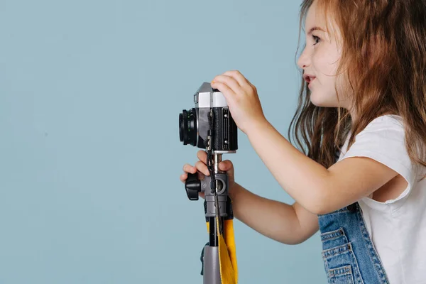 小さな女の子は青の上にヴィンテージミラーカメラで画像を撮っています. — ストック写真