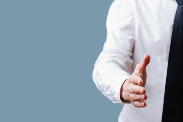 Empresario en camisa blanca extendiendo la mano, listo para el apretón de manos sobre azul — Foto de Stock