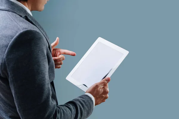 Businessman is looking at black screen of his tablet over blue background