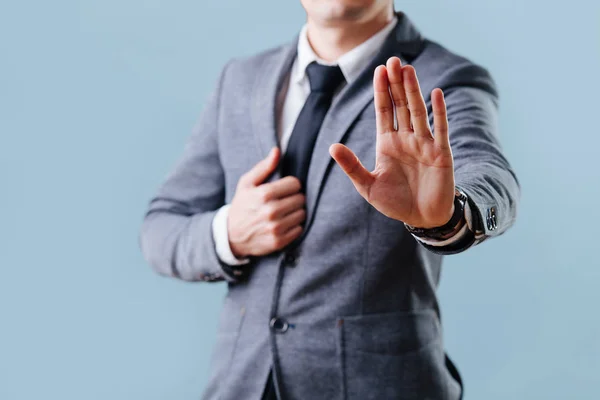 Hombre de negocios en traje haciendo gesto de parada, sosteniendo su palma hacia afuera sobre azul — Foto de Stock