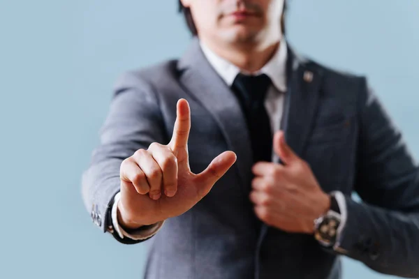 Empresario en traje haciendo gesto de objeción, sosteniendo el dedo índice sobre azul — Foto de Stock