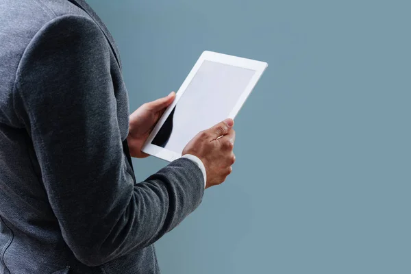 Zakenman is op zoek naar zwart scherm van zijn Tablet over blauwe achtergrond — Stockfoto