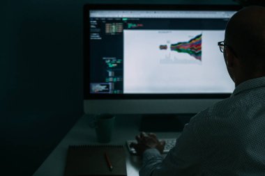 Geliştirici, masanın arkasında çalışıyor, ekrandaki diyagramı analiz ediyor