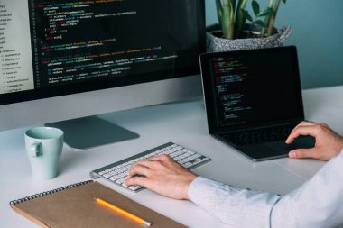 Programcı, masanın arkasında çalışıyor, siyah ekrandaki kodu analiz ediyor..