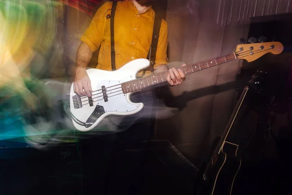 Bas gitarist playing on the white guitar, motion blurred with afterimages of him