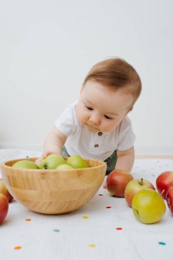 Bebek evde elmalarla oynuyor.