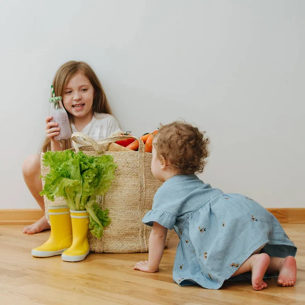 Маленька мила дівчинка повзе до великих мішків з овочами — стокове фото