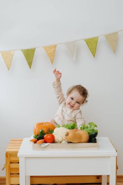 Bebek masada sebzelerle oynuyor.