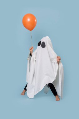 Cadılar bayramında beyaz hayalet gibi giyinmiş küçük çocuk komik duruşlar sergiliyor.