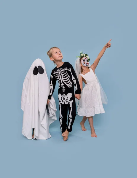 Tre bambini in costumi di Halloween che si tengono per mano sullo sfondo blu — Foto Stock