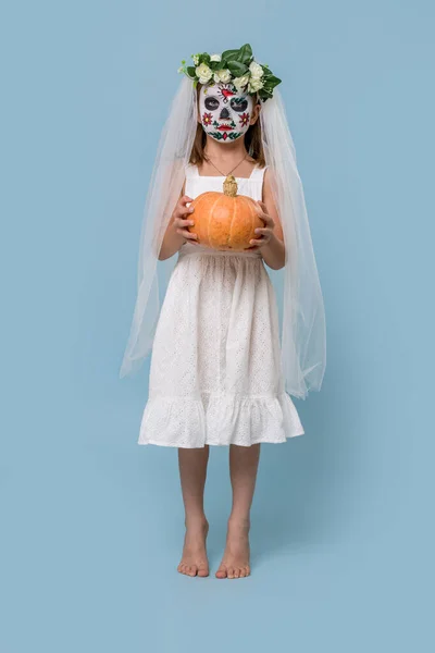 Bambina in abito da sposa indossa dipinto spaventoso teschio maschera su sfondo blu — Foto Stock