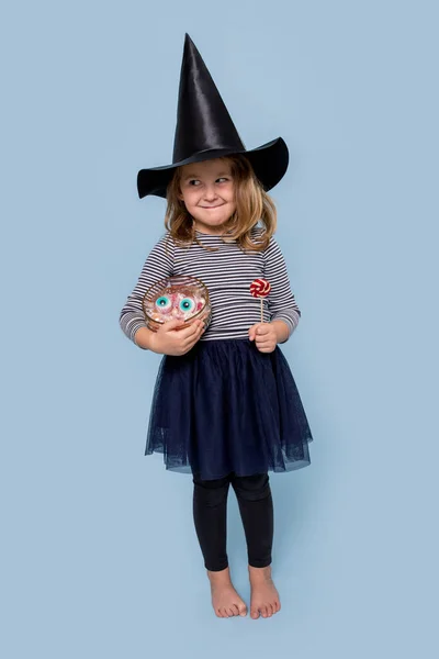 Roztomilá holčička v kostýmu čarodějnice na Halloween drží sladkosti a lízátko — Stock fotografie