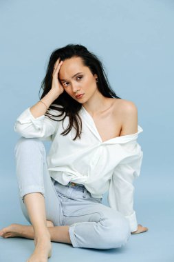 Seksi, güzel bir esmerin portresi ciddi yüz ifadesi ve beyaz vitiligo kirpikleriyle. Elbise gömleği giyiyor, bir omzu çıplak. Yerde oturuyor, eline yaslanıyor..