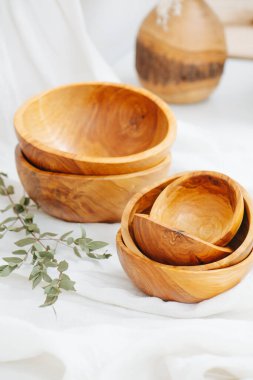 Boş ahşap kaselerin bileşimi, pürüzsüz ve beyaz kumaşla verniklenmiş. Kapatın. Kırpılmış. Tahta desen. Kurumuş dal ve ahşap vazo onun bir parçası..