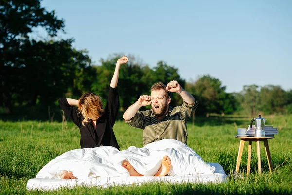 Man and woman waking up from a nap in the middle of a countryside — Stock Photo, Image