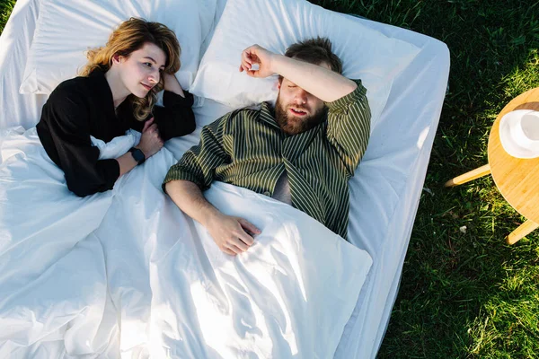 Dışarıda çimlerin üzerinde dinlenen çift. Karısı erkeğinin uyumasını izliyor. — Stok fotoğraf