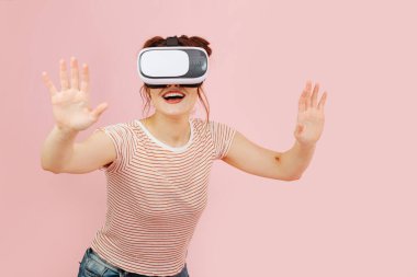 VR kulaklıklı, tuhaf gülümseyen genç bir kadın. Yönünü bulmaya çalışıyor, elleriyle uzayı keşfetmeye çalışıyor..