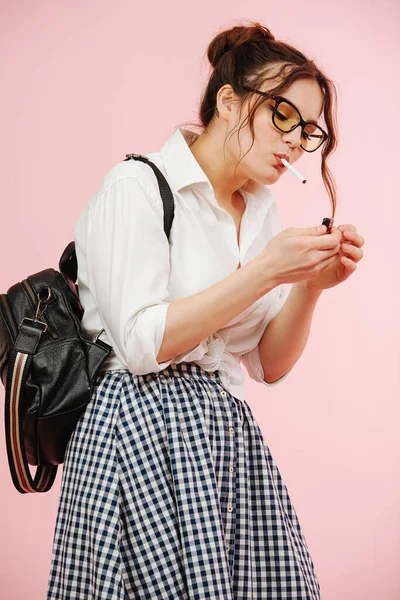 Jovem rebelde em uma roupa de estudante acendendo cigarro sobre rosa — Fotografia de Stock